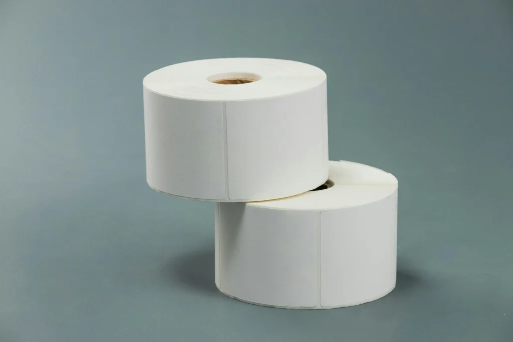 Duas bobinas de papel higiênico brancas empilhadas em fundo cinza, destacando sua forma circular e uso doméstico. Ideal para higiene pessoal.
