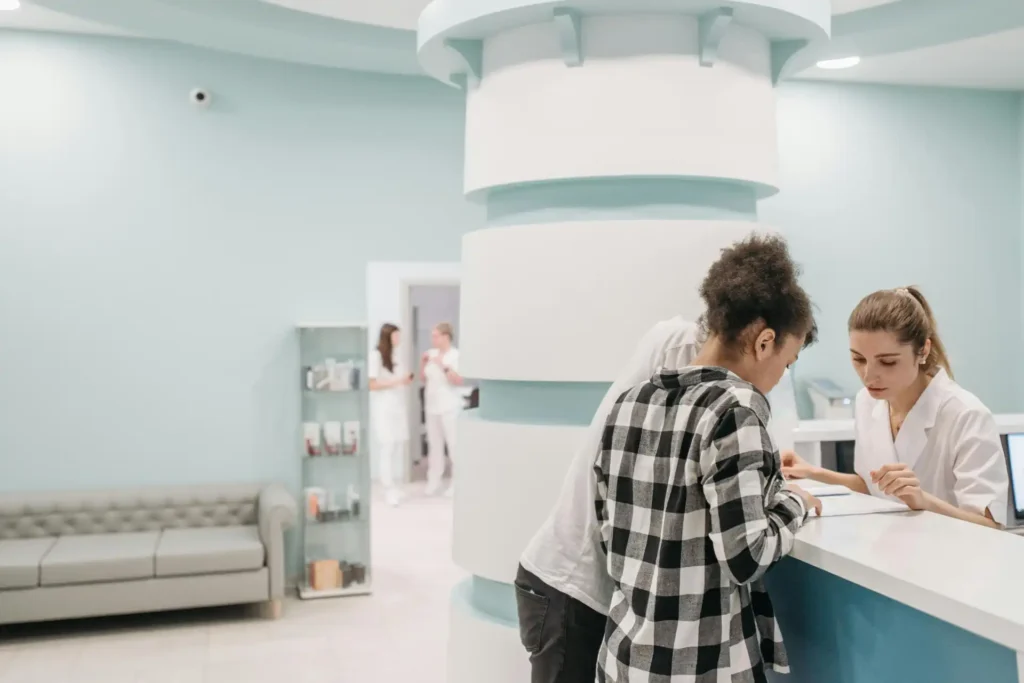 Pacientes em uma recepção de clínica médica conversando com profissional de saúde