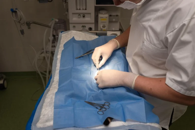 Cirurgião realizando procedimento cirúrgico em ambiente hospitalar com instrumentos médicos sobre uma mesa.